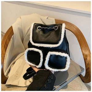 Close-up of contrast black leather backpack with fluffy white plush trim and chain straps