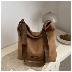 Close-up of brown suede tote bag featuring adjustable leather strap and vintage buckle
