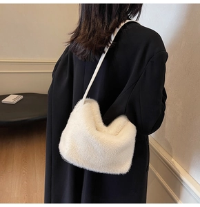 Modischer Look einer weißen Pelzimitat-Hobo-Tasche kombiniert mit einem schwarzen Mantel
