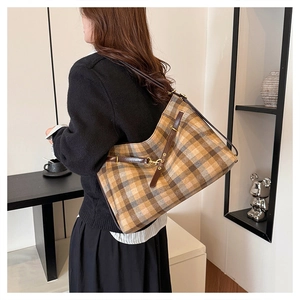 Grand sac cabas à carreaux porté par un mannequin pour un look décontracté chic