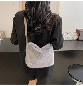 Detail der grauen Plüsch-Schultertasche mit Lederriemen über einem schwarzen Blazer