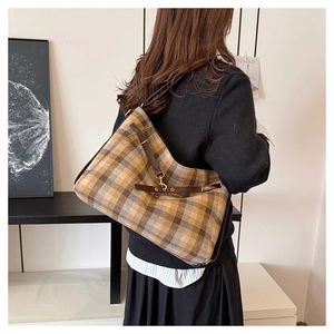 Détail d'un grand sac cabas à carreaux marron avec bandoulière en cuir et boucle
