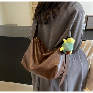 Detailed view of brown PU leather tote bag with lychee texture and green turtle pendant