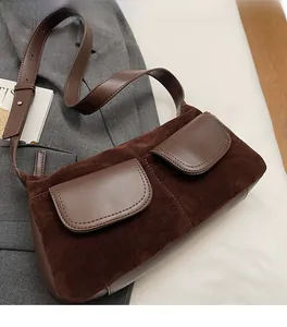 Detail of brown suede shoulder bag with dual leather flap pockets and adjustable strap