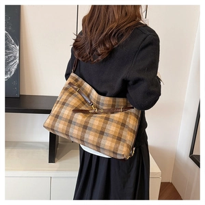 Détail du sac cabas en tartan vintage montrant la bandoulière en cuir et la boucle