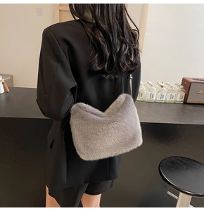 Graue Kunstfell-Schultertasche am Model getragen, weiche Textur in stilvollem Ambiente