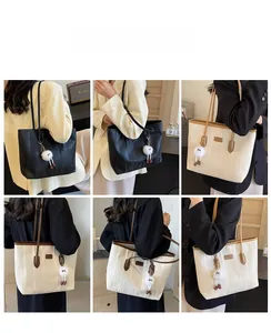 Detail view of large pleated tote bag with contrast leather handles and plush charm