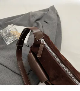 Close-up of smooth metal zipper and matte suede texture on vintage dark brown crossbody bag