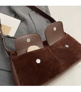 Detail of dual front pockets with magnetic closures on coffee suede shoulder bag