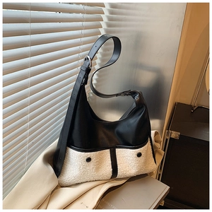 Detail of hobo bag featuring black leather, white shearling texture and metal buckles