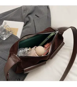 Macro view of a large brown suede handbag interior showing phone and umbrella