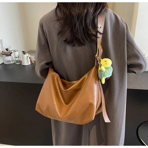 Detail of caramel brown PU leather tote bag with a cute green plush turtle charm
