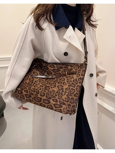 Grand sac fourre-tout à motif léopard avec bordures en cuir porté sur un manteau élégant