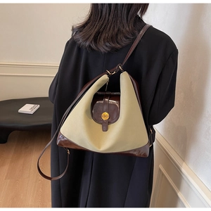 Detail of canvas tote bag with brown leather trim and golden N buckle on model
