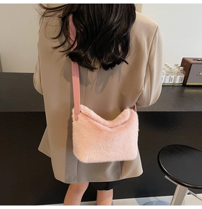 Rosa Plüsch-Beuteltasche mit Lederriemen an einem Modell in gemütlicher Café-Szene