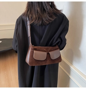 Detail of vintage brown suede shoulder bag showing stitching and flap pocket texture