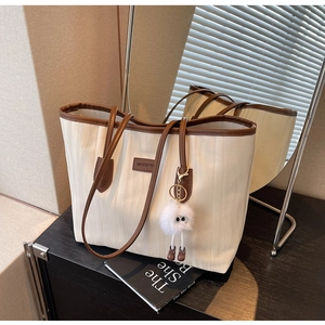 Detailed macro view of the cream tote bag with water ripple texture and brown contrast trim