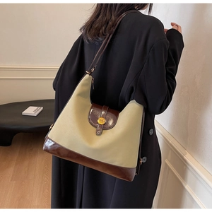 Detail shot of beige canvas tote with brown leather trim and gold buckle on model