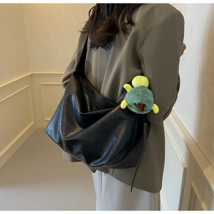 Rear view of model wearing a large black leather tote bag with a green turtle charm