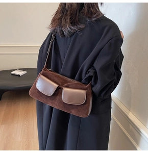 Detail of dark brown suede shoulder bag with dual flap pockets and retro aesthetic