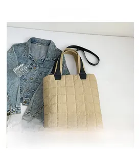 Detailed view of sand quilted nylon tote bag with black straps on denim background