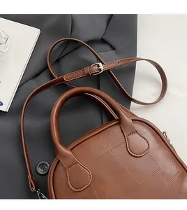 Detail view of dark brown vintage square bag with embossed pattern and silver hardware