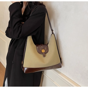 Detail of contrast color shoulder bag with gold N hardware on model in black blazer