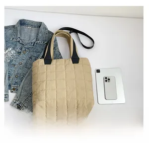 Top view of beige quilted tote bag showing large capacity with tablet and denim jacket