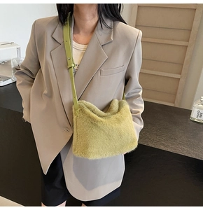 Detail der grünen Plüschtasche mit verstellbarem Lederriemen auf khakifarbenem Blazer