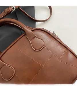 Detail of brown vintage square bag featuring fine hand-stitched grid and leather texture