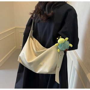Detailed back view of a cream tote bag with soft pleated texture and plush insect charm