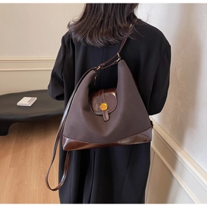 Detail of a large coffee-colored hobo bag with a gold logo buckle and premium texture
