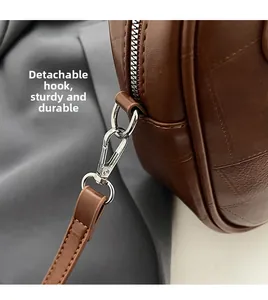 Detailed view of silver metal hook and D-ring on brown leather crossbody bag