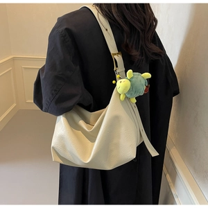 Detail of beige faux leather tote bag featuring a cute green turtle plush pendant