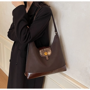 Detail of dark brown leather tote bag showing metallic N logo and frosted texture