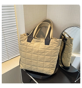 Close-up of beige quilted nylon tote bag showing square stitching and durable black straps