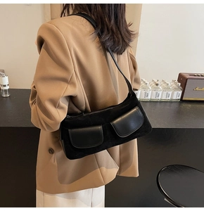Detail of black matte shoulder bag with dual leather pockets shown on a model's outfit