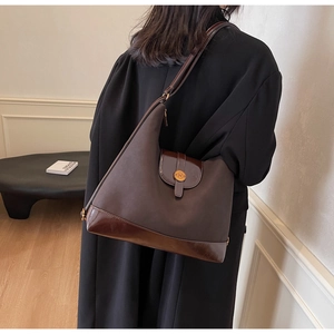Close-up of large dark brown tote bag with vintage circular N logo and matte leather finish