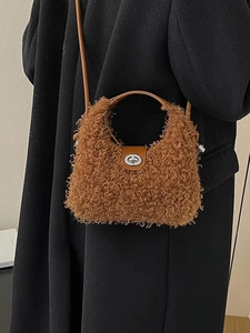 Brown faux shearling crossbody bag with leather handles shown on a black wool coat