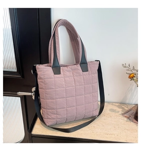 Close-up of quilted nylon fabric and black reinforced handles on a pink tote bag