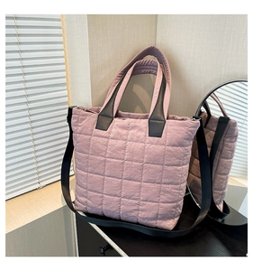 Detail of light pink quilted nylon tote bag with thick handles and black strap hooks