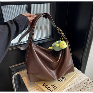 Detail of a brown large-capacity Hobo bag with adjustable strap and a plush charm