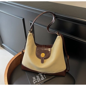 Macro detail of khaki canvas tote with dark brown leather trim and golden metal N buckle