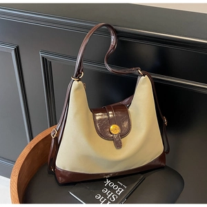 Close-up of retro beige canvas hobo bag with dark brown leather trim and gold N buckle
