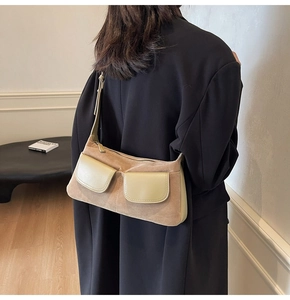 Detail of camel suede shoulder bag with contrast flap pockets on a black blazer
