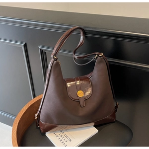 Detail of dark brown tote bag showing contrast textures and round gold metal logo