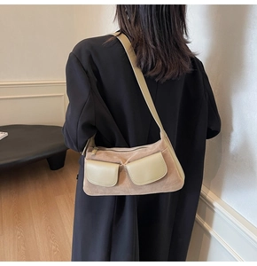 Chic beige suede shoulder bag styled with black blazer in a modern interior setting