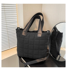 Detail of black quilted puffer tote bag featuring silver hardware and adjustable strap