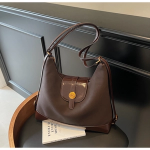 Detail of dark brown leather tote bag showing vintage stitching and golden N logo buckle