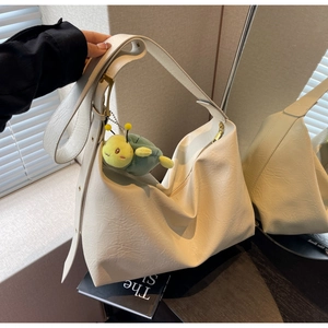 Detail of cream large hobo bag with adjustable strap and green plush charm